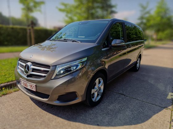 Lariva's glanzende Mercedes-Benz V-Class minivan geparkeerd op zonnige parkeerplaats, omgeven door natuur.