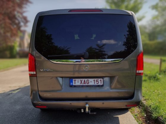 Achterkant van Lariva's Mercedes-Benz V-Class van geparkeerd op rustige, boomrijke straat.